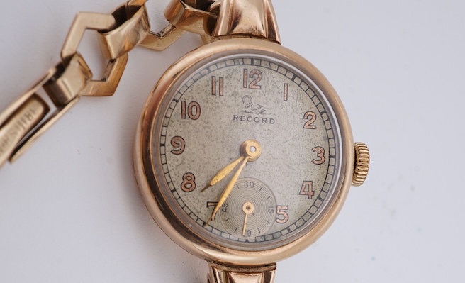A lady's 9ct gold Record manual wind wrist watch, with Arabic dial and subsidiary seconds, on a 9ct gold bracelet, gross weight 16 grams. Condition - fair
